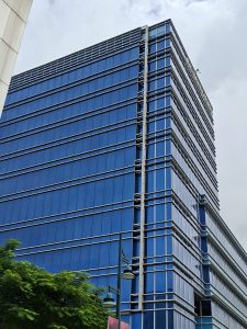 Modern high-rise building with vibrant blue glass panels and horizontal silver bands across each floor.