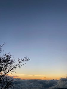 A serene twilight landscape showcases a gradient sky transitioning from deep blue at the top to warm oranges and yellows near the horizon. 
