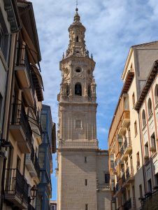 Baroque clock tower of Santo Domingo de la Calzada Cathedral framed between historic residential buildings in La Rioja, Spain.