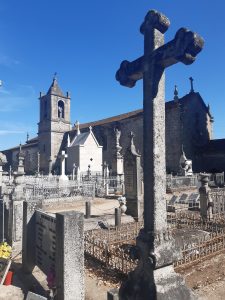 A stone cross in a cemetery with a chapel and bell tower in Vila Real, Portugal.