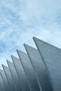 Modern architectural roof with sharp, repeating geometric shape against a soft blue sky.