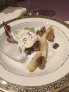 A plate of creamy cheese with pears, figs, mixed greens, and berry sauce.