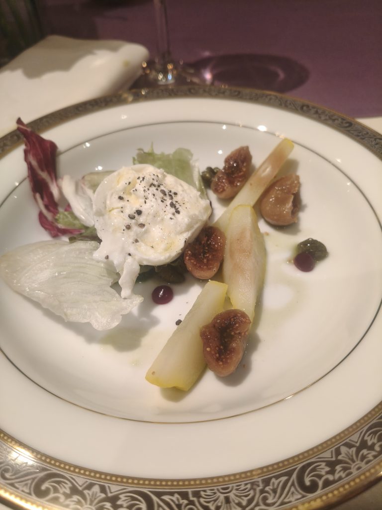 A plate of creamy cheese with pears, figs, mixed greens, and berry sauce.