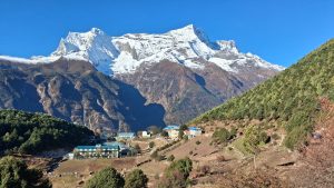 Buildings at Everest Base Camp with snow-capped mountains under a clear blue sky.

