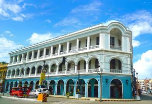Calle Real in Iloilo City, featuring a historic multi-story building with a bright blue ground floor.