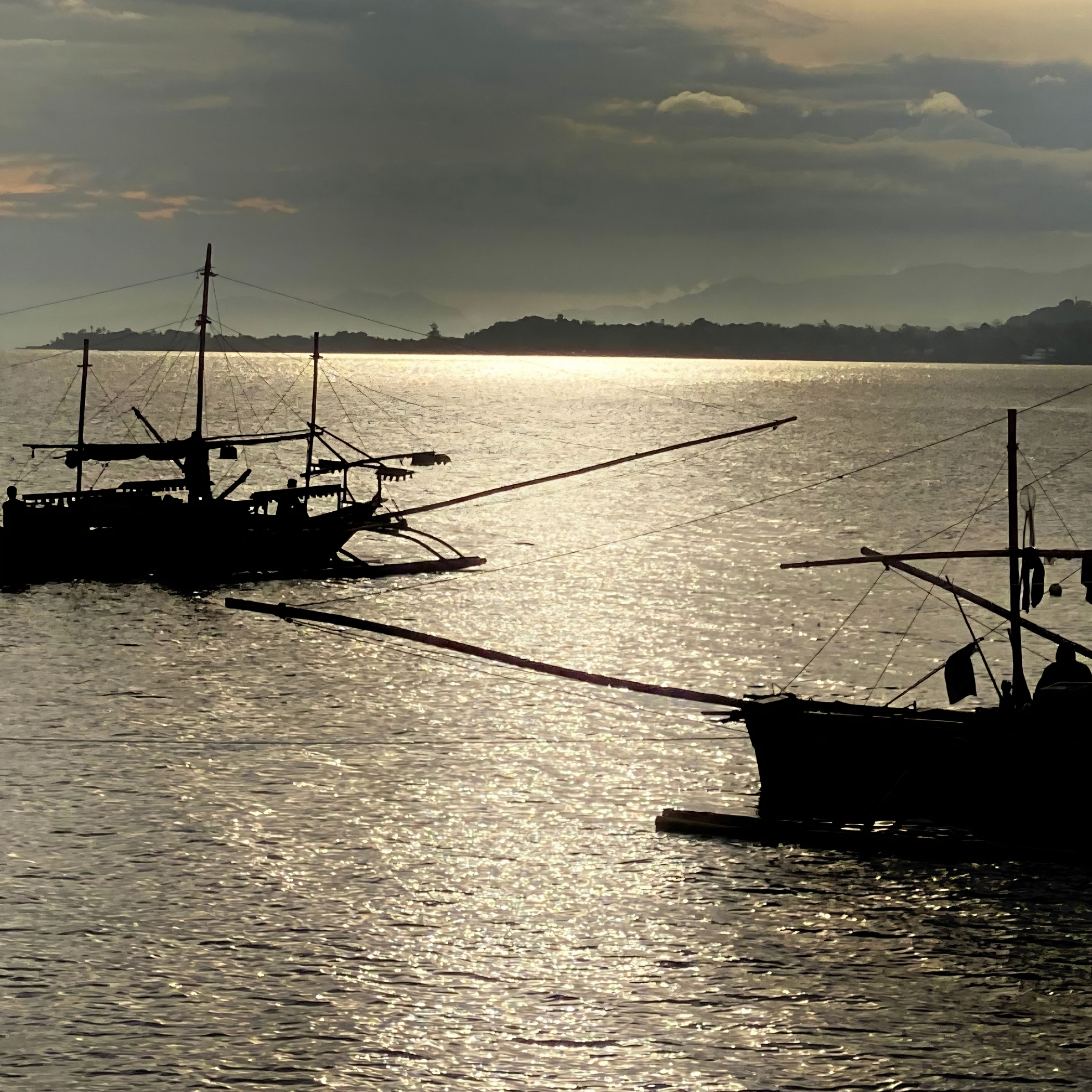 Two fishing boats head across the calm sea, carried by the gentle afternoon waters.