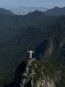 Aerial view of Christ the Redeemer in Brazil with mountains and coastline in the background.
