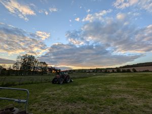 A tractor in the green cloudy French countryside and ray of light from the sunset.