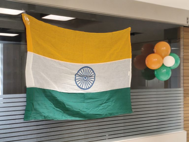 Indian flag with yellow, white, and green sections, blue wheel, and colorful balloons.