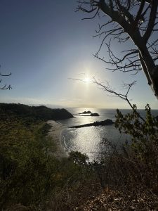 
A panoramic view of a coastal scene featuring a shimmering body of water under a bright sun.