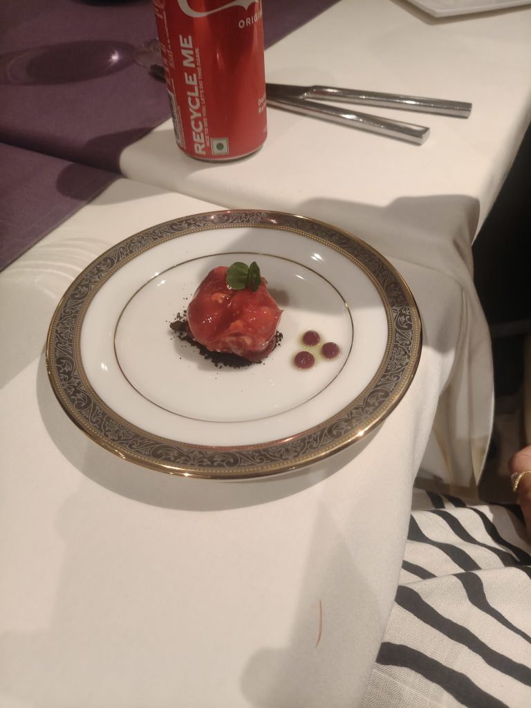 A small dessert with red sauce is served on a decorative white plate.