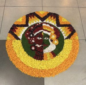 A colorful circular floral design depicting a split face with vibrant headdresses and concentric petal rings.