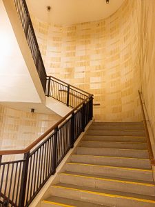 A warm, curved staircase with dark railings and warm beige walls.