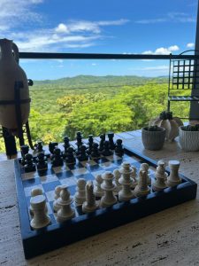 
A chessboard sits on a textured, light-colored surface, with the pieces arranged ready for play. 
