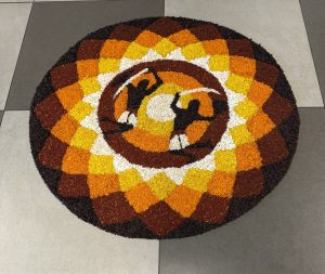 Colorful circular decorative rug with geometric patterns and two figures in the center.