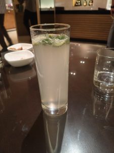 A glass of sparkling lemon soft drink on a dark wooden table.
