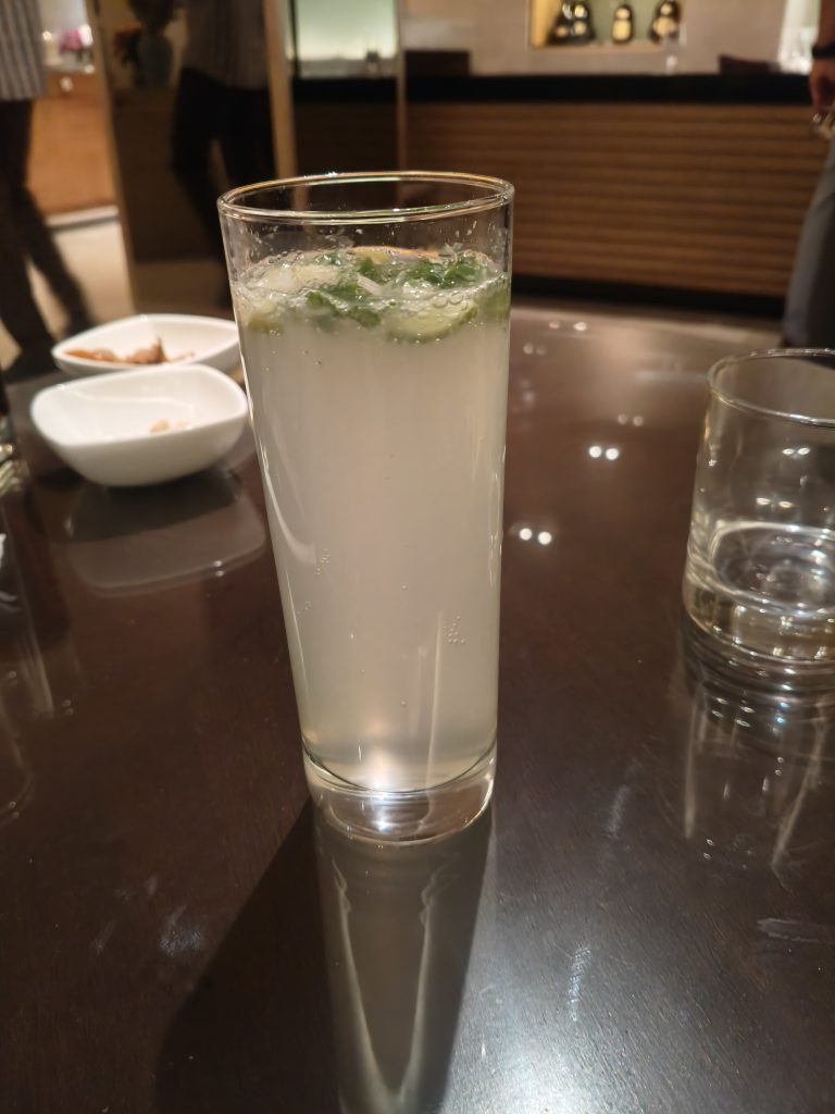 A glass of sparkling lemon soft drink on a dark wooden table.