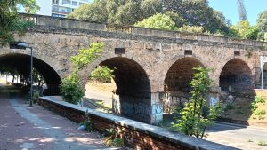 Side of a stone bridge over streets and some graffiti.