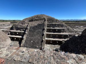 
Ancient stone temple pyramid rising above a flat landscape under a clear sky.