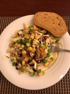 
A plate of creamy pasta with grilled chicken, mushrooms, green onions, and croutons.