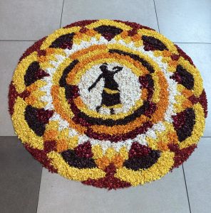 A colorful circular floral design with concentric petal patterns and a central silhouette of a woman.