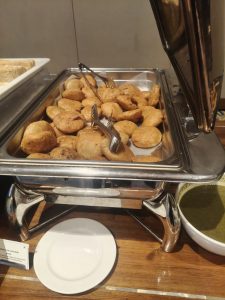 Freshly made Indian kachoris served in a buffet dish with green chutney.
