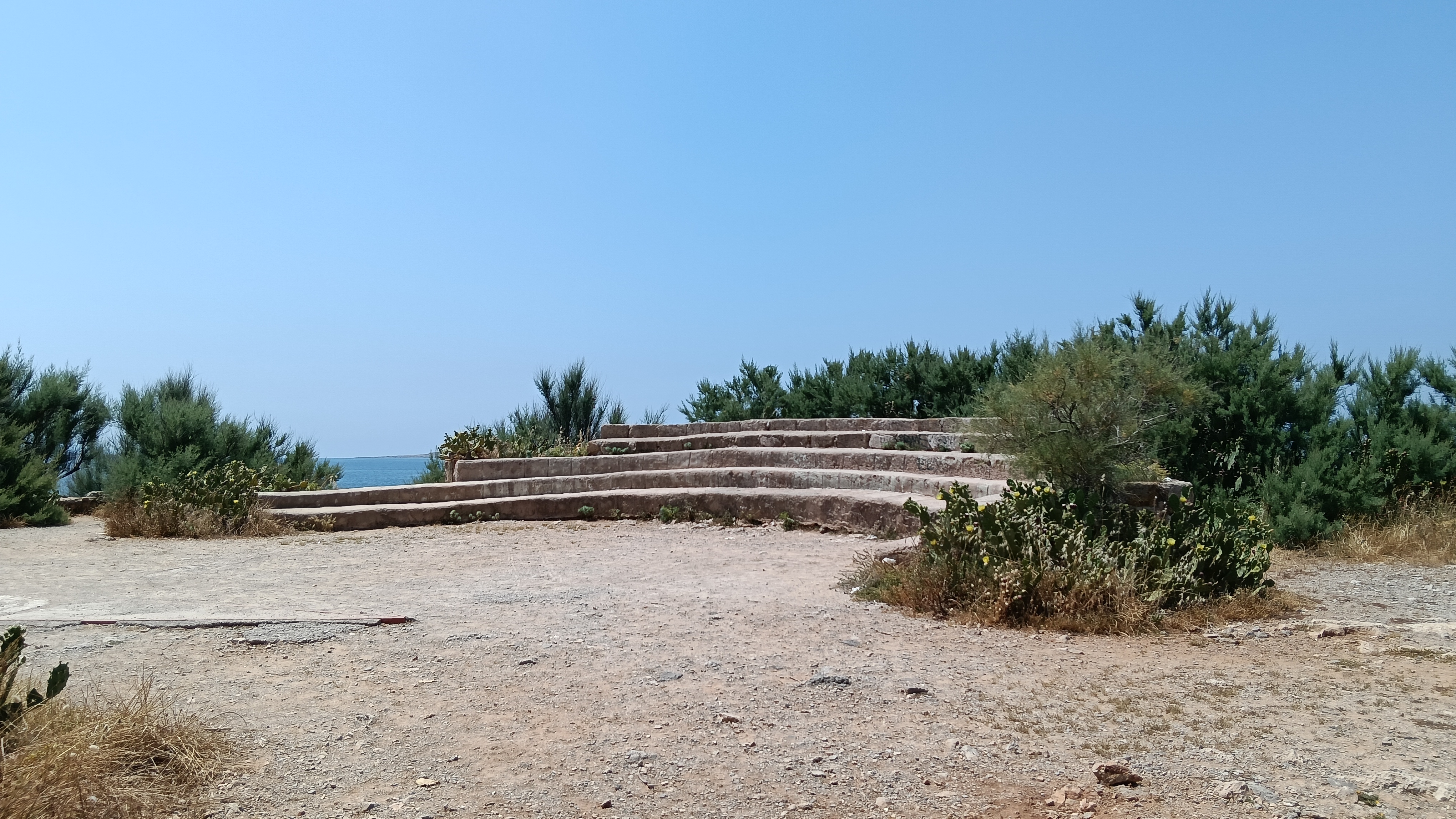 Rock-made circular stands over a sand field on a clear day.