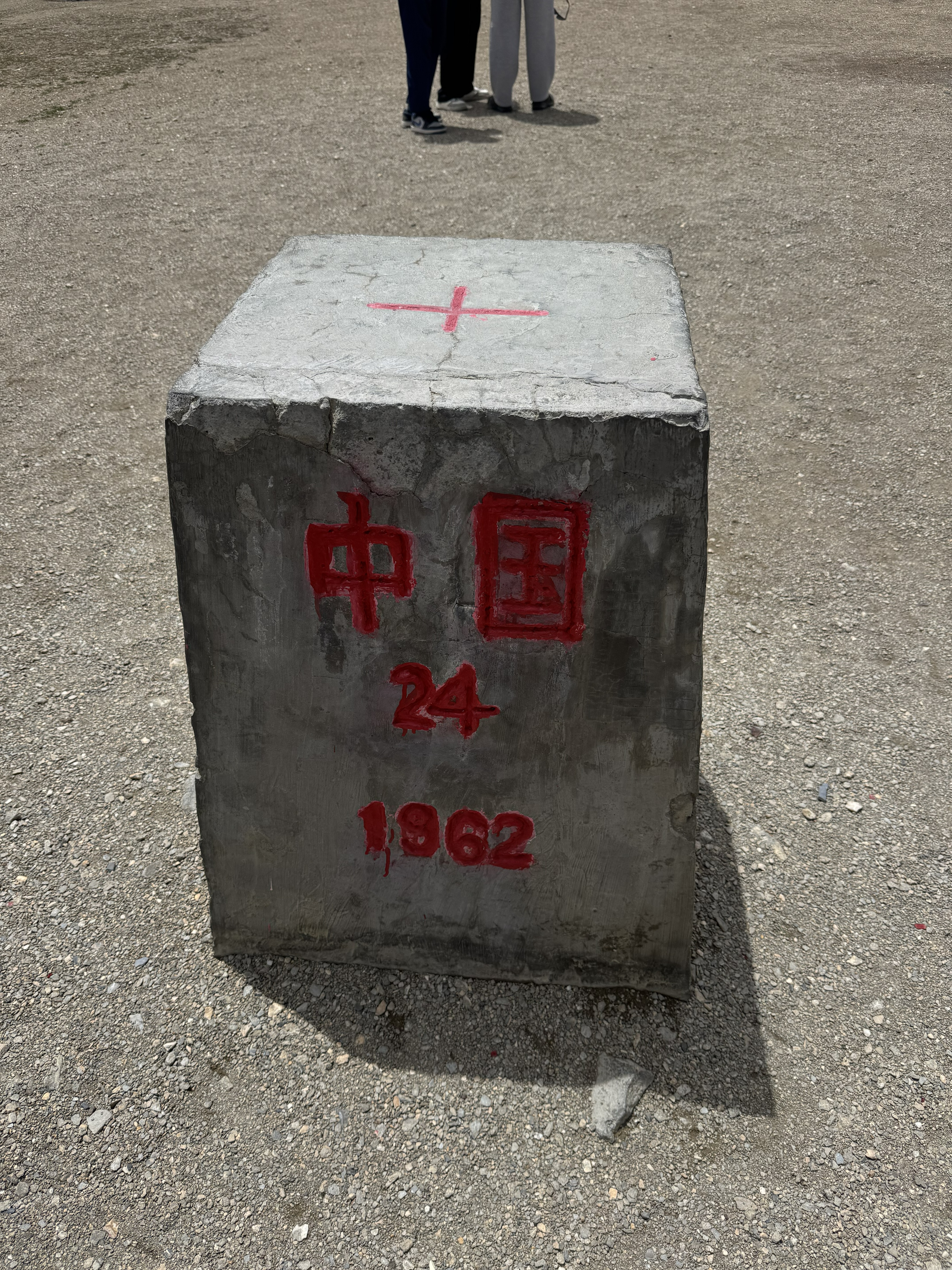 Close-up of international border pillar No. 24 marked “China,” with the year 1962, standing on dry gravel ground.