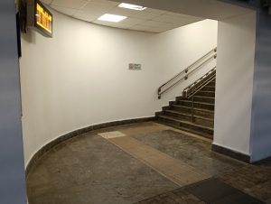 Corner of the train station stairs, featuring a departures screen and a smoking notice.