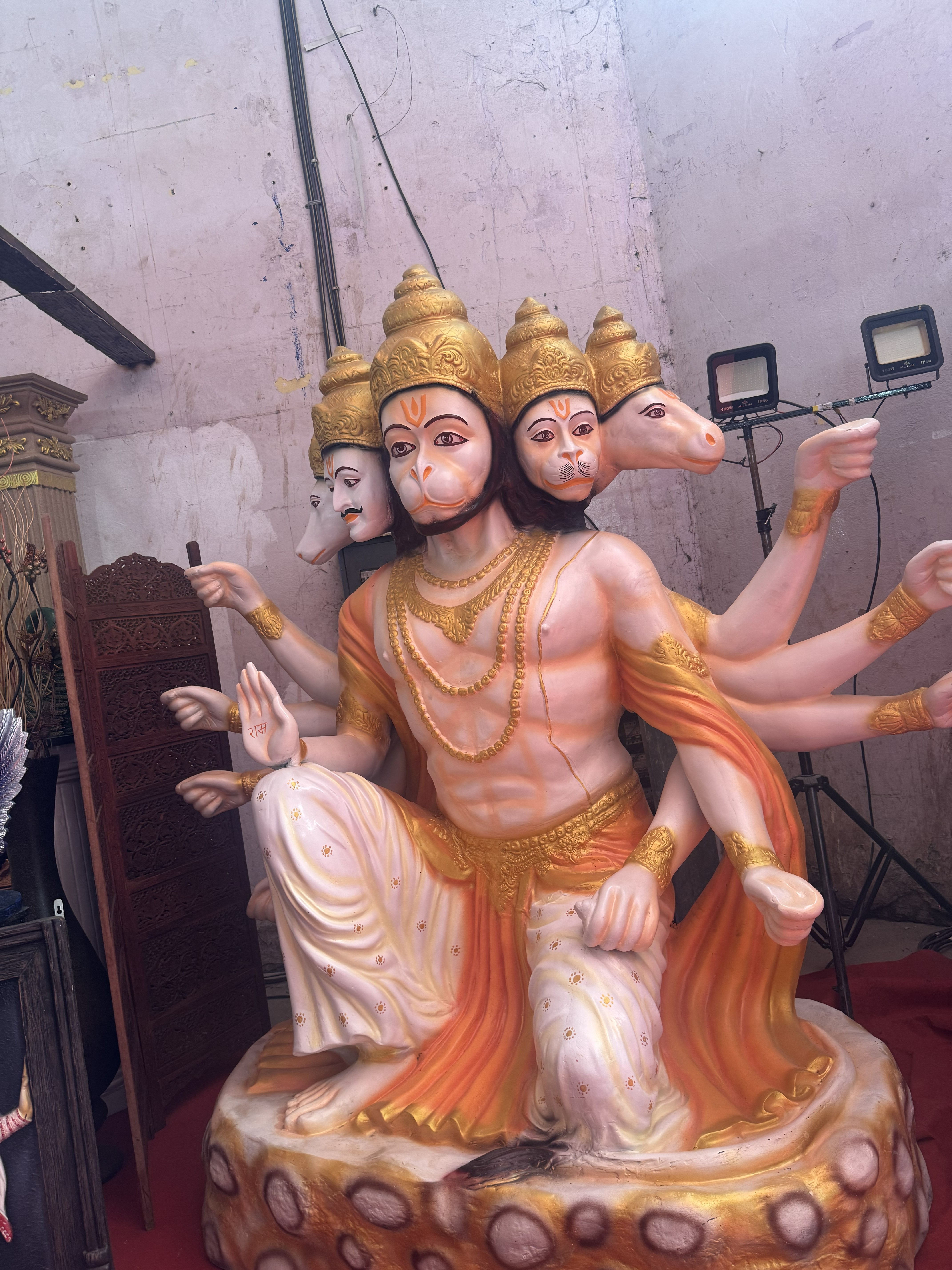 A multi-armed, five-faced statue of Panchamukhi Hanuman painted in vibrant gold and orange shades