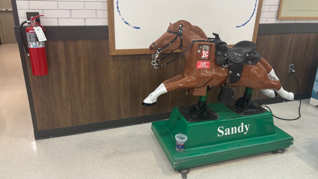 An electric pony in a grocery store.  It's built to look like it's running, and has "Sandy" written on the base.