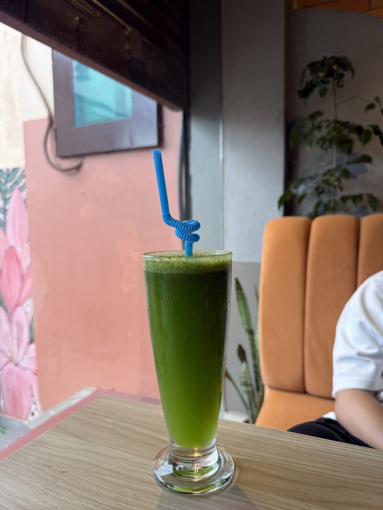 Green mint lemonade in a clear glass on a wooden table.