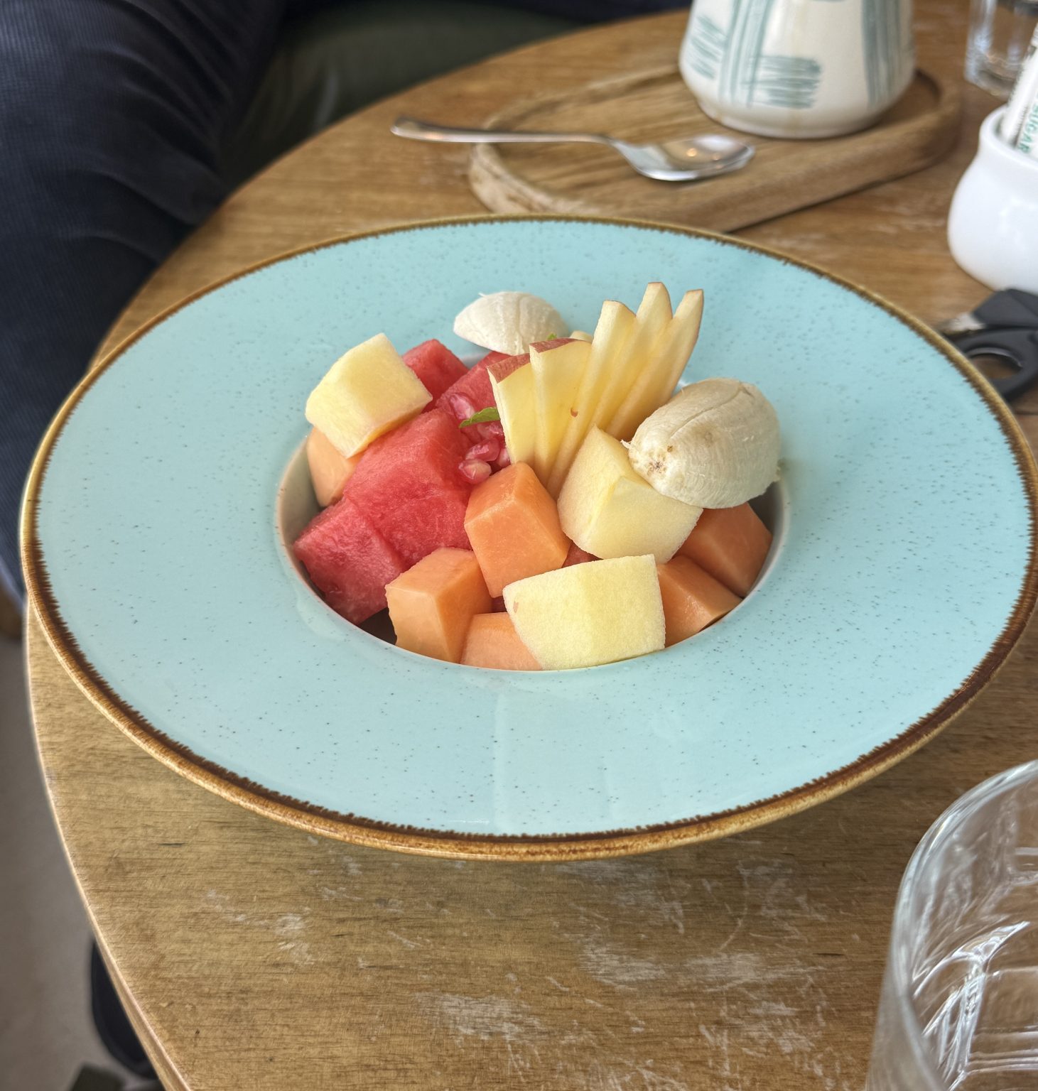 A vibrant bowl of assorted fresh fruit is placed on a wooden table.