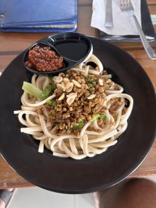 A black plate holds a serving of thick, white noodles that are slightly glossy. 
