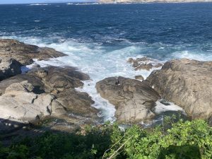 Sea waves creating white foam among rocky formations along the Galician coast.
