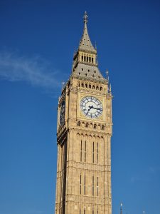 Detailed close-up shot of the Elizabeth Tower / big ben clock face and spire against a clear blue sky.