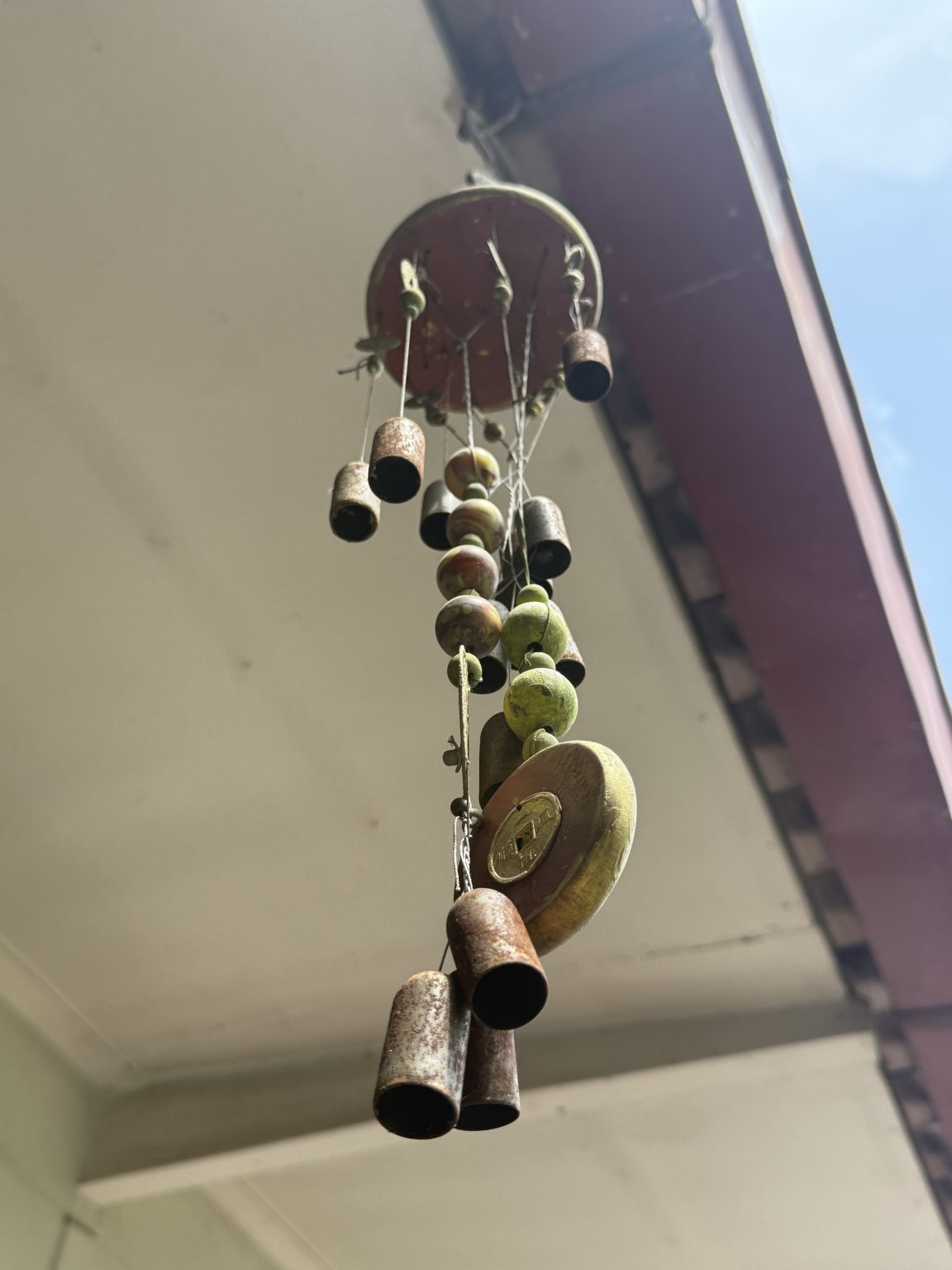 A decorative wind chime hangs from a ceiling, composed of various objects that create a whimsical appearance.