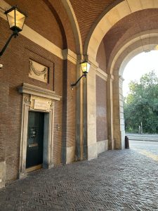 Brick architecture with arched doorways and traditional lanterns along an urban passage.
