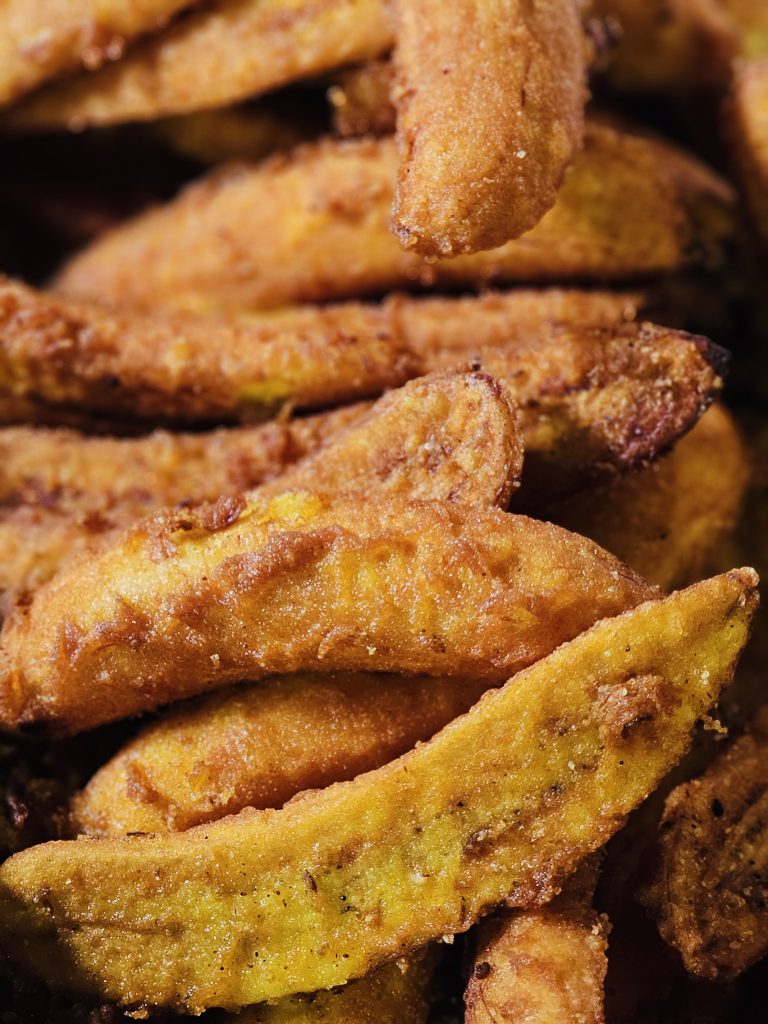 Close-up view of freshly fried golden-brown banana fritters, highlighting their crisp texture and warm colors. Location: Vallichira, Kottayam, Kerala.
