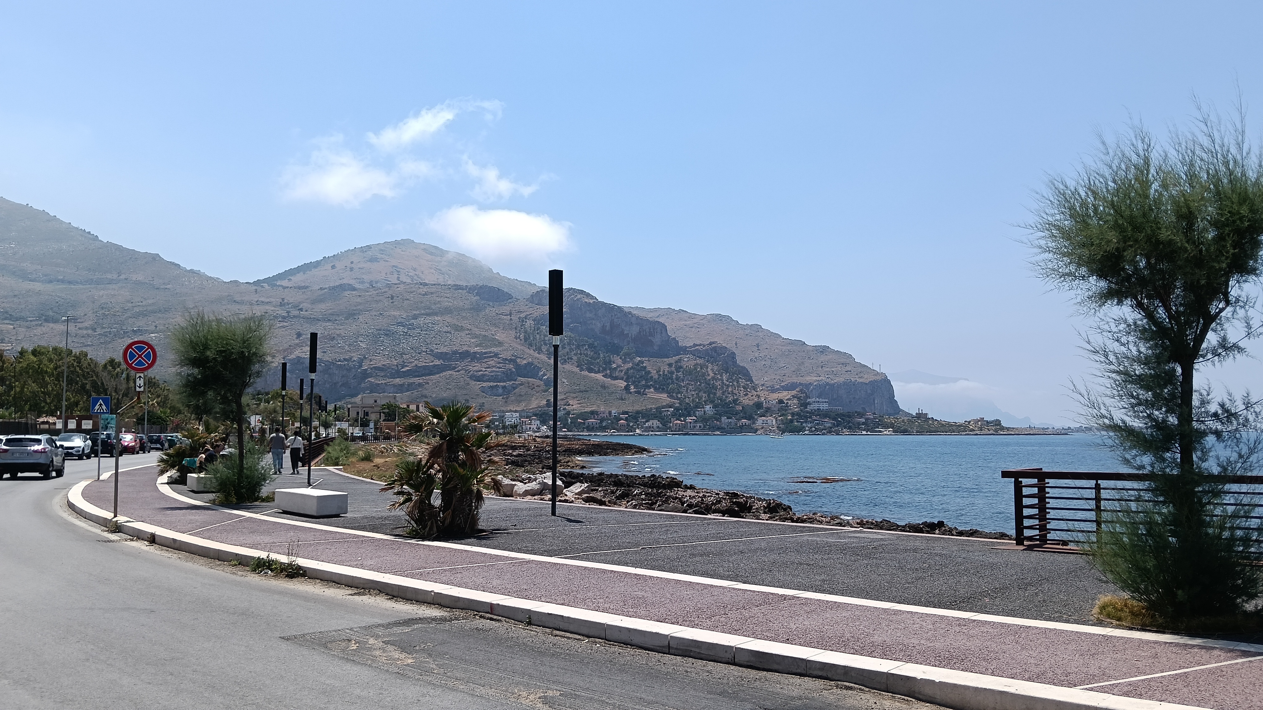 Different pathways and a winding road beside the sea, with a distant valley in the background.
