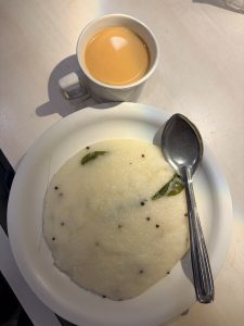 Plate of freshly prepared upma served with a cup of tea.