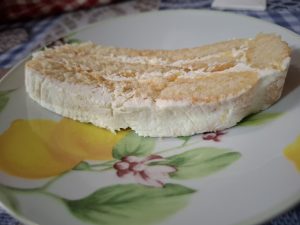 Lemon tiramisu on a white plate. The plate is decorated with leaves and lemons.