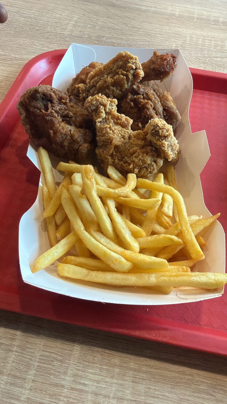 A plate of chrispy fried chicken and fries on a paper plate