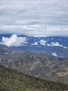 High-altitude mountain landscape with dry, rugged ridges under heavy clouds.