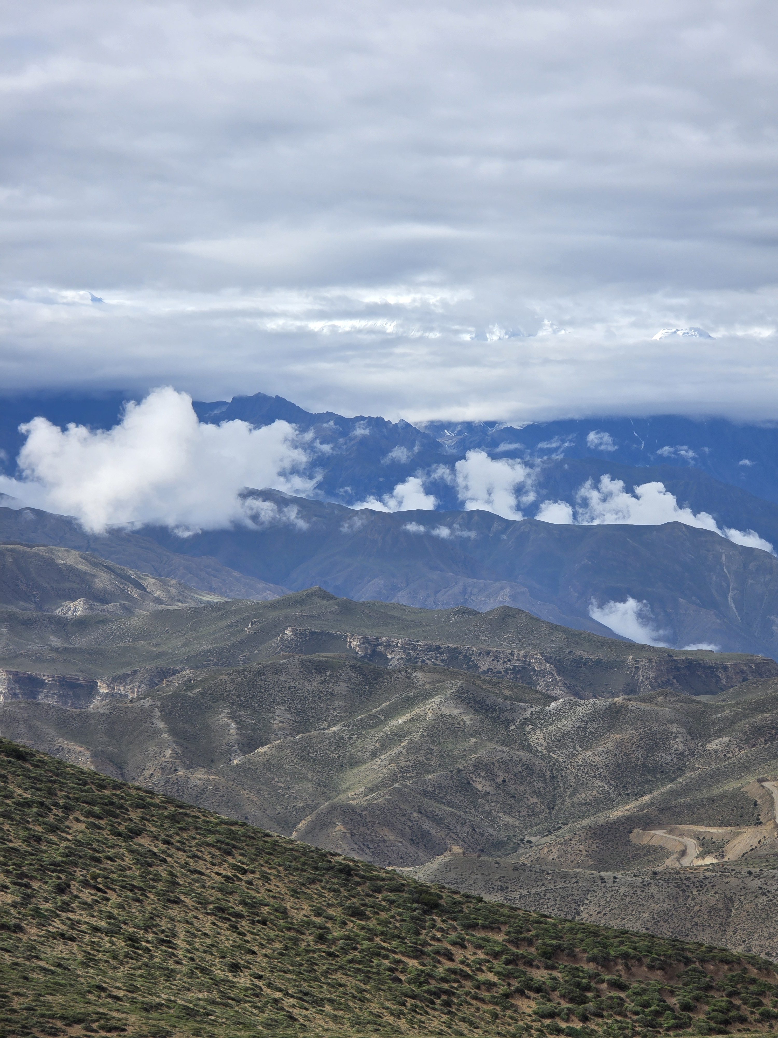 High-altitude mountain landscape with dry, rugged ridges under heavy clouds.