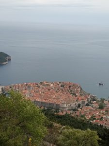 Aerial view of the walled Old Town of Dubrovnik, Croatia, featuring traditional terracotta roofs and the Adriatic Sea.