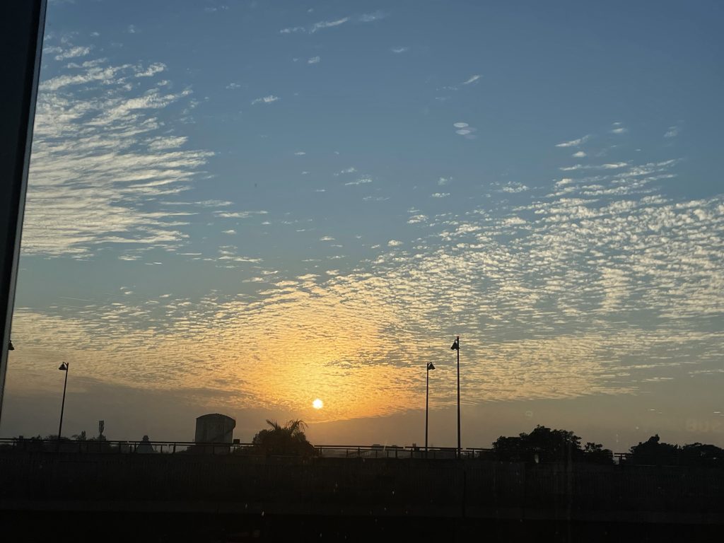 Late evening, before sunset. Hue of white and yellow, with the sun and clouds spread in the sky.
