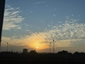 Late evening, before sunset. Hue of white and yellow, with the sun and clouds spread in the sky.