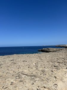 Rocky coastline overlooking the blue sea under a clear sky.
