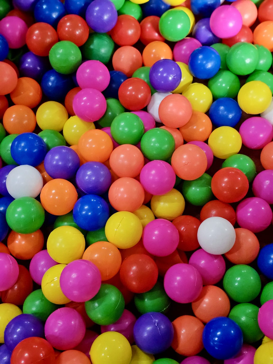 A colorful collection of bright plastic balls fills the frame with vivid shades of red, yellow, green, blue, pink, and purple. The repeating shapes and strong colors create a cheerful abstract composition. Location: Ayamkudy, Kottayam, Kerala.